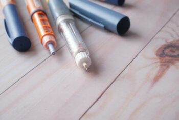 Insulin pens on wooden background, close up
