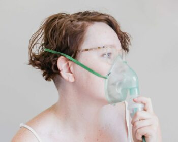 a woman in a white tank top with a mask on her face
