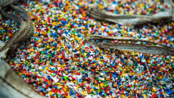 Sack of sorted multicoloured shredded plastic garbage at waste recycling factory